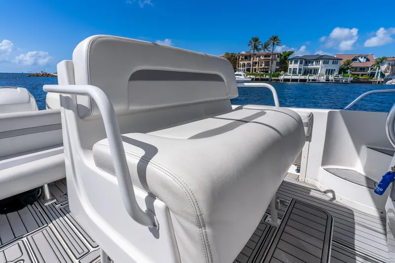Slide: The Image of 2003 Intrepid 348 Walkaround boat interior with white seating, overlooking waterfront homes. - 28