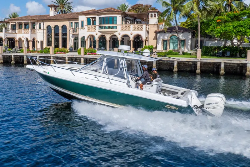 Slide: The Image of 2003 Intrepid 348 Walkaround boat cruising near luxury waterfront homes. - 8