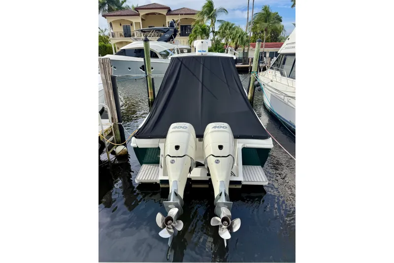 Slide: The Image of 2003 Intrepid 348 Walkaround boat with twin outboard engines docked, covered with a black tarp. - 2