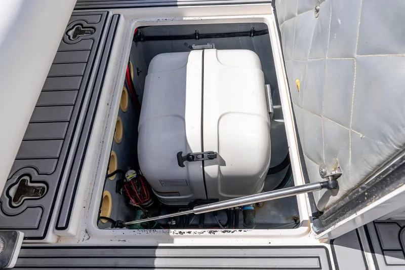 Slide: The Image of Storage compartment of a 2003 Intrepid 348 Walkaround boat, featuring a secured white container. - 35