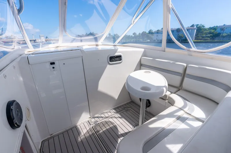 Slide: The Image of 2003 Intrepid 348 Walkaround boat interior with seating and table, under clear blue skies. - 17