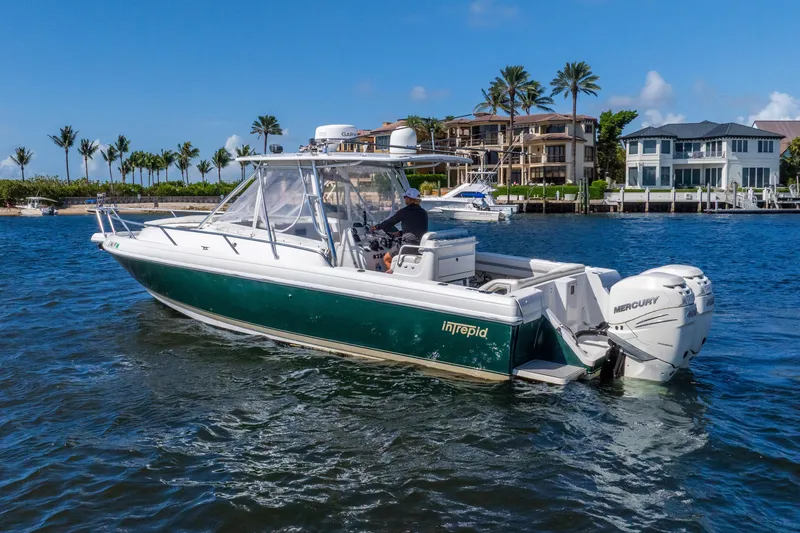 Slide: The Image of 2003 Intrepid 348 Walkaround boat cruising near waterfront homes and palm trees. - 16