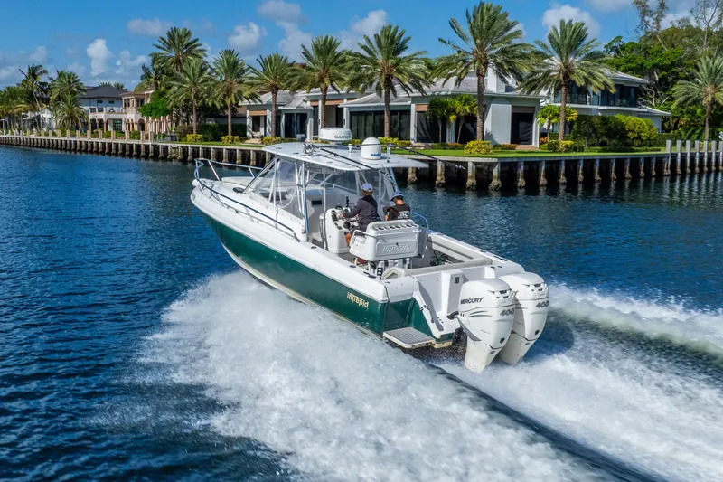 Slide: The Image of 2003 Intrepid 348 Walkaround cruising on a scenic waterway with palm trees and luxury homes. - 6