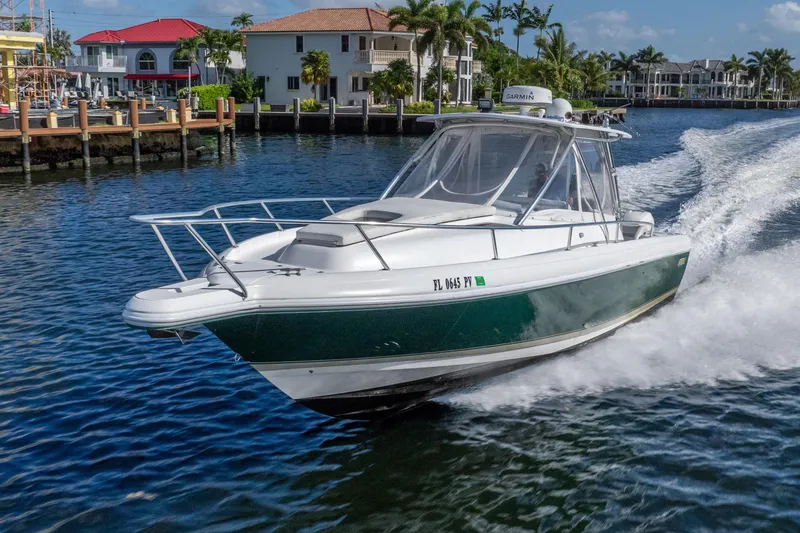 Slide: The Image of 2003 Intrepid 348 Walkaround boat cruising in a scenic waterfront area. - 2