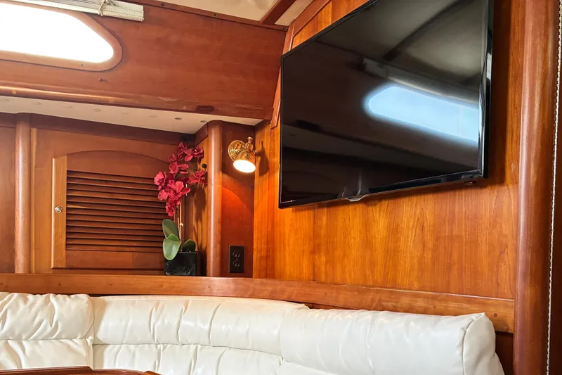 Slide: The Image of Interior of 1999 Sabre 452 yacht with TV, wood paneling, and white seating. - 27