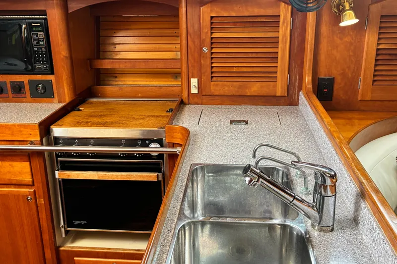Slide: The Image of 1999 Sabre 452 yacht kitchen with wooden cabinetry, stainless steel sink, and modern appliances. - 21