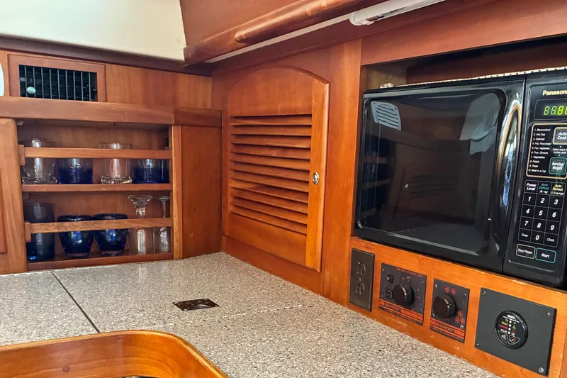 Slide: The Image of 1999 Sabre 452 yacht kitchen with microwave, wooden cabinetry, and glass storage. - 19