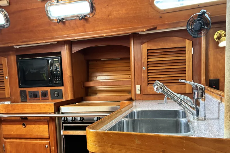 Slide: The Image of 1999 Sabre 452 yacht kitchen with wooden cabinetry, stainless steel sink, and built-in microwave. - 22