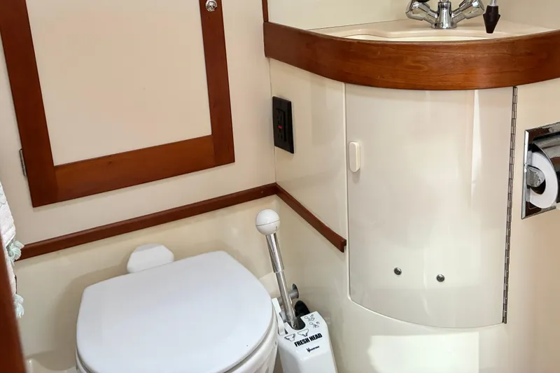 Slide: The Image of 1999 Sabre 452 yacht bathroom with toilet, sink, and wooden accents. - 44