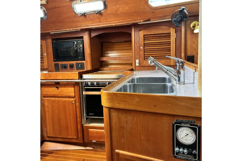 Slide: The Image of 1999 Sabre 452 yacht kitchen with wooden cabinetry, stainless steel sink, and modern appliances. - 23