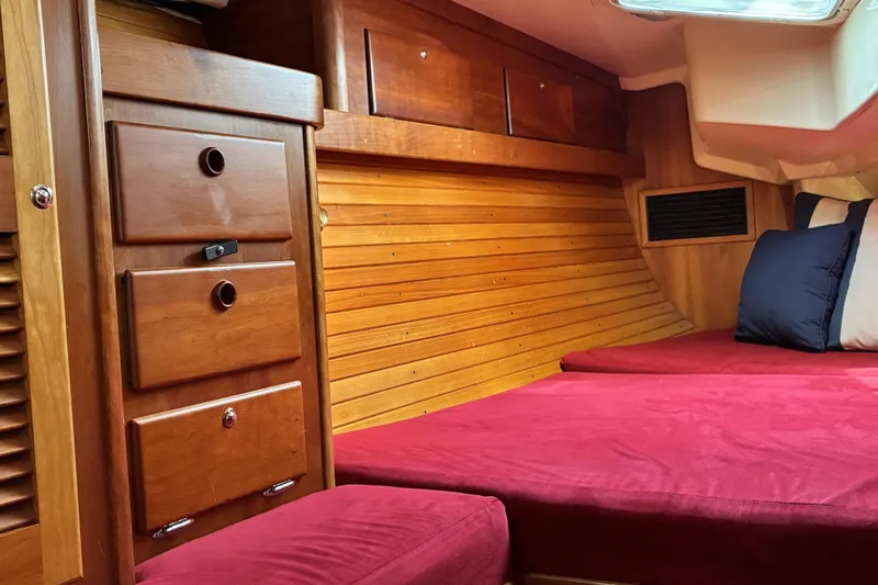 Slide: The Image of Interior of a 1999 Sabre 452 yacht with wooden cabinetry and red bedding. - 46