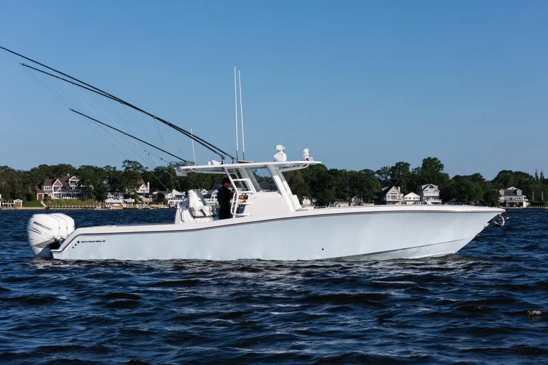 Slide: The Image of 2022 Invincible 39 Open Fisherman boat cruising on a sunny day near shoreline homes. - 2