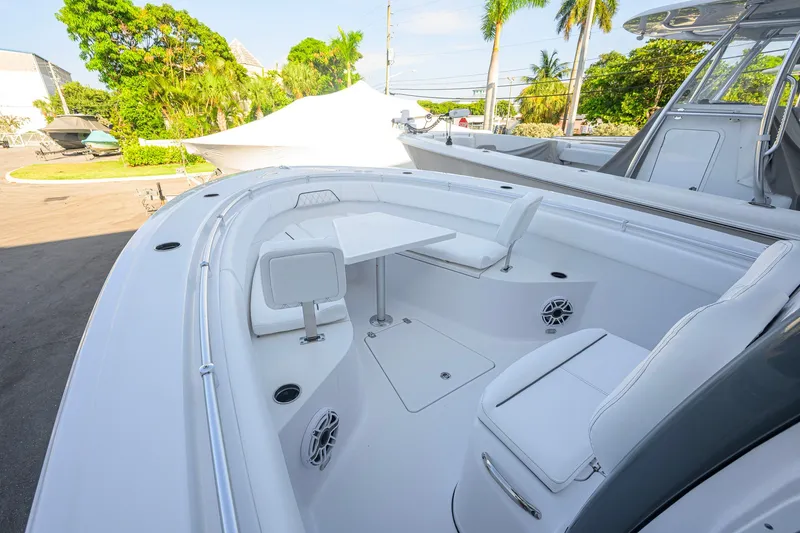 Slide: The Image of 2027 Sportsman Open 262 Center Console boat with sleek seating and table, surrounded by lush greenery. - 10