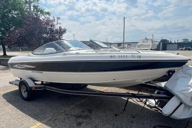 Slide: The Image of 2008 Stingray 195 LX boat on trailer in parking lot, under a partly cloudy sky. - 2