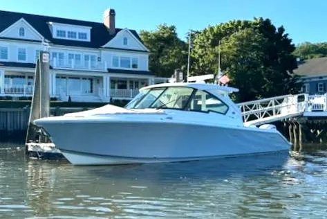 Slide: The Image of 2024 Pursuit DC 326 Dual Console boat docked near waterfront homes. - 26