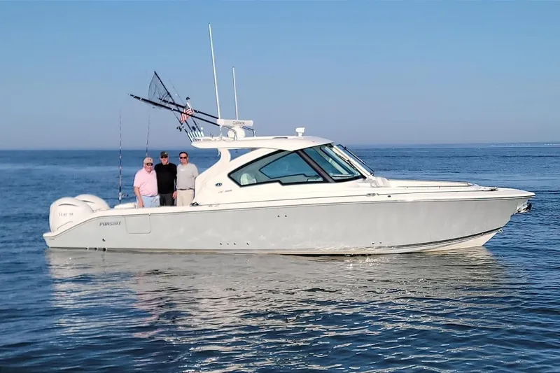 Slide: The Image of 2024 Pursuit DC 326 Dual Console boat on calm ocean waters with three people onboard. - 8