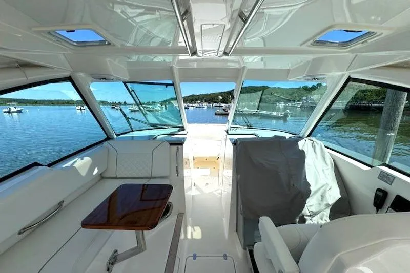 Slide: The Image of Interior view of 2024 Pursuit DC 326 Dual Console boat with scenic water backdrop. - 37