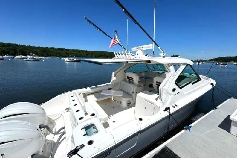 Slide: The Image of 2024 Pursuit DC 326 Dual Console boat docked on a sunny day, featuring sleek design and spacious seating. - 36