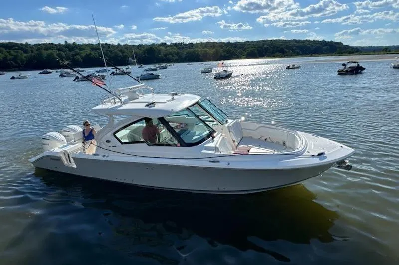 Slide: The Image of 2024 Pursuit DC 326 Dual Console boat cruising on a sunny lake with other boats. - 35