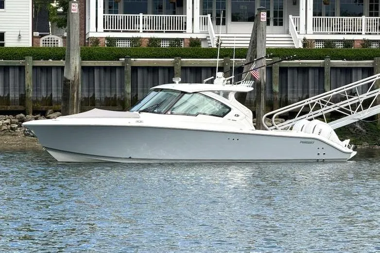 Slide: The Image of 2024 Pursuit DC 326 Dual Console boat docked by waterfront homes. - 25