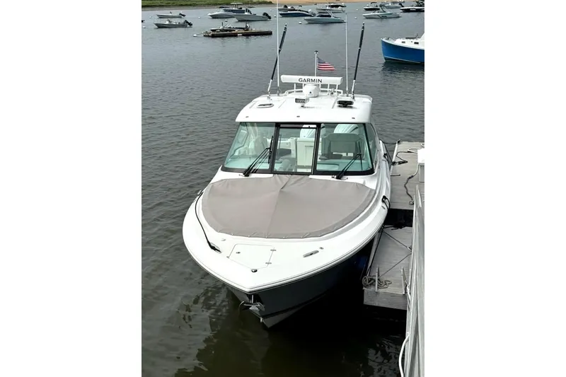 Slide: The Image of 2024 Pursuit DC 326 Dual Console boat docked on calm water. - 24