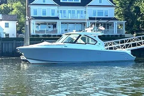 Slide: The Image of 2024 Pursuit DC 326 Dual Console boat docked near waterfront homes. - 30