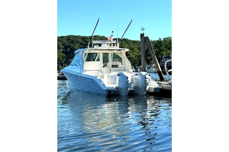 Slide: The Image of 2024 Pursuit DC 326 Dual Console boat docked in a serene marina setting. - 28