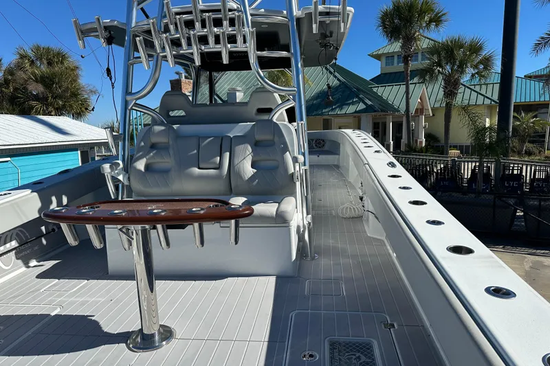 Slide: The Image of 2023 Freeman 42LR boat interior with seating and rod holders, docked near palm trees. - 10