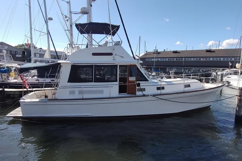 Slide: The Image of 1996 Grand Banks Eastbay 40 Flybridge yacht docked at marina under clear sky. - 1