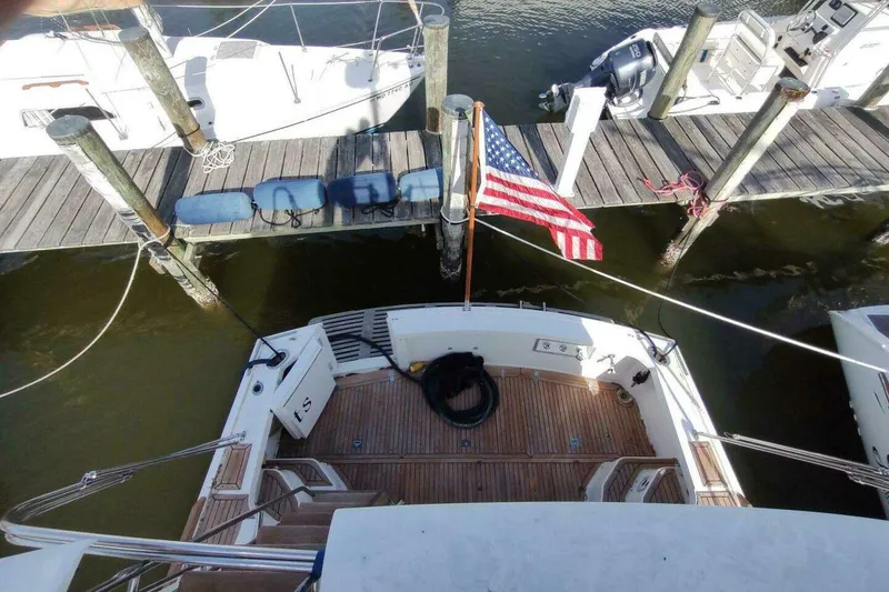 Slide: The Image of 1996 Grand Banks Eastbay 40 Flybridge docked with American flag, wooden deck view. - 13