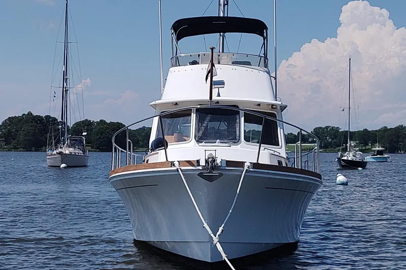 Slide: The Image of 1996 Grand Banks Eastbay 40 Flybridge yacht anchored on a serene lake with sailboats. - 7