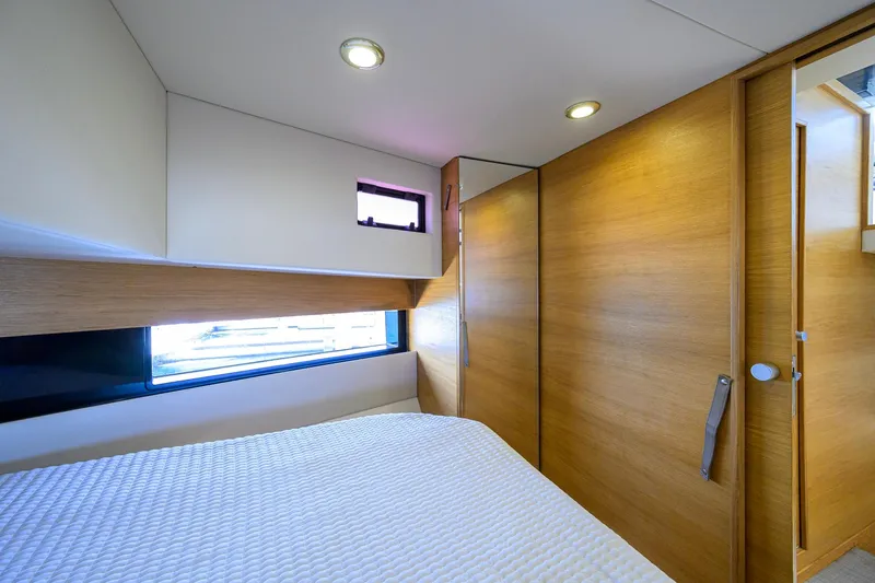 Slide: The Image of Interior cabin of 2023 De Antonio Yachts D42 Open, featuring modern wood paneling and cozy bedding. - 24