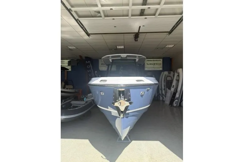 Slide: The Image of 2026 Monterey Elite 25 OB boat in showroom, front view, blue hull. - 1