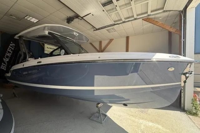 Slide: The Image of 2026 Monterey Elite 25 OB boat in showroom, featuring sleek blue and white design. - 2