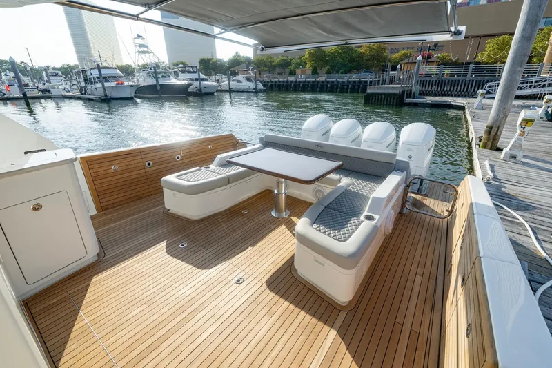 Slide: The Image of 2026 Valhalla V-55 Sport Yacht deck with seating, table, and outboard motors at marina. - 10