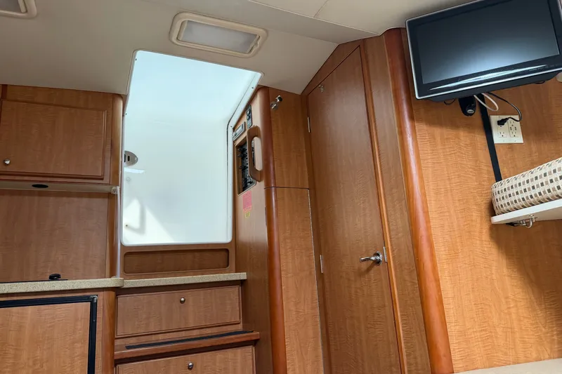 Slide: The Image of 2007 Luhrs 31 Open cabin interior with wood finish, TV, and storage cabinets. - 19