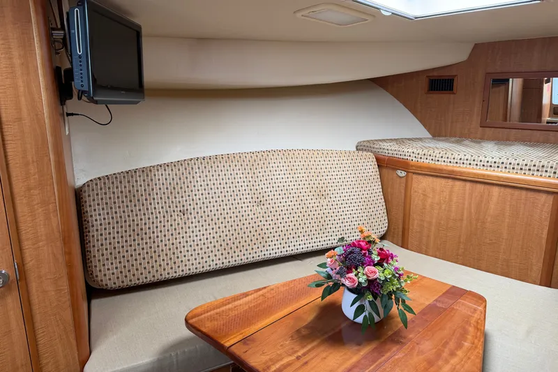 Slide: The Image of 2007 Luhrs 31 Open cabin interior with TV, seating, and floral centerpiece. - 17