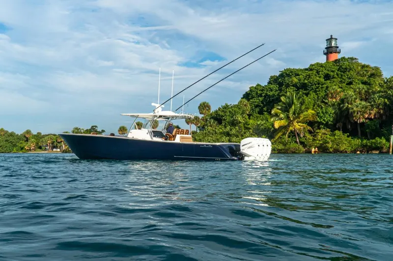 Slide: The Image of 2026 Valhalla Boatworks V-41 cruising near lush island with lighthouse in background. - 1