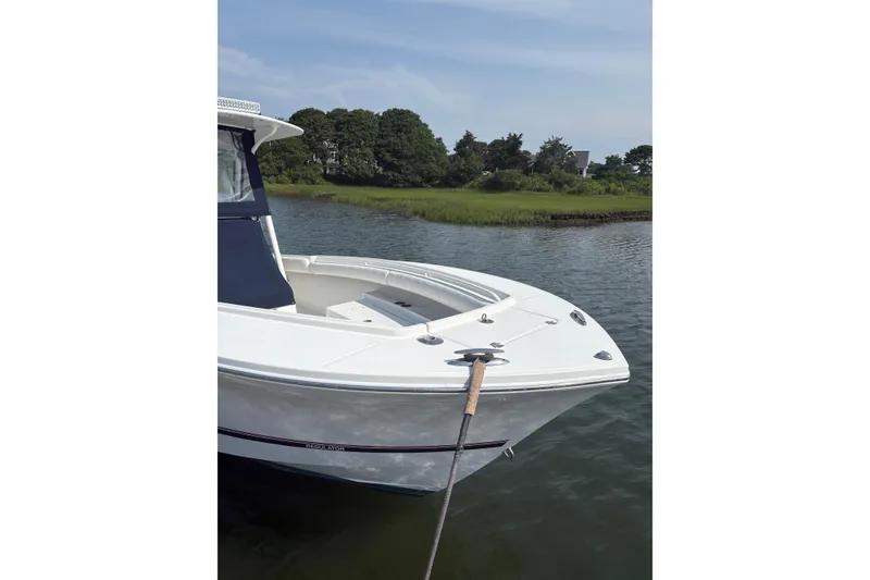 Slide: The Image of 2015 Regulator 25 boat docked on calm water with lush greenery in the background. - 11