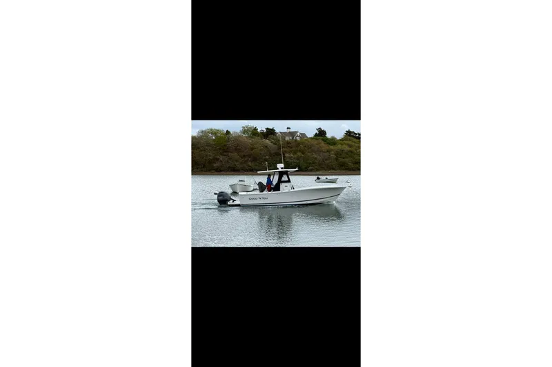 Slide: The Image of 2015 Regulator 25 boat cruising on calm water near a wooded shoreline. - 2
