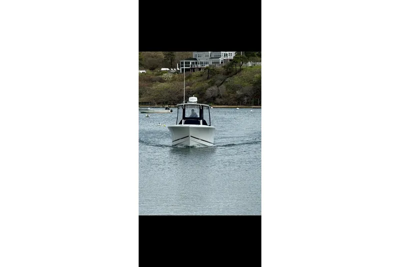 Slide: The Image of 2015 Regulator 25 boat cruising on a calm lake with scenic background. - 3