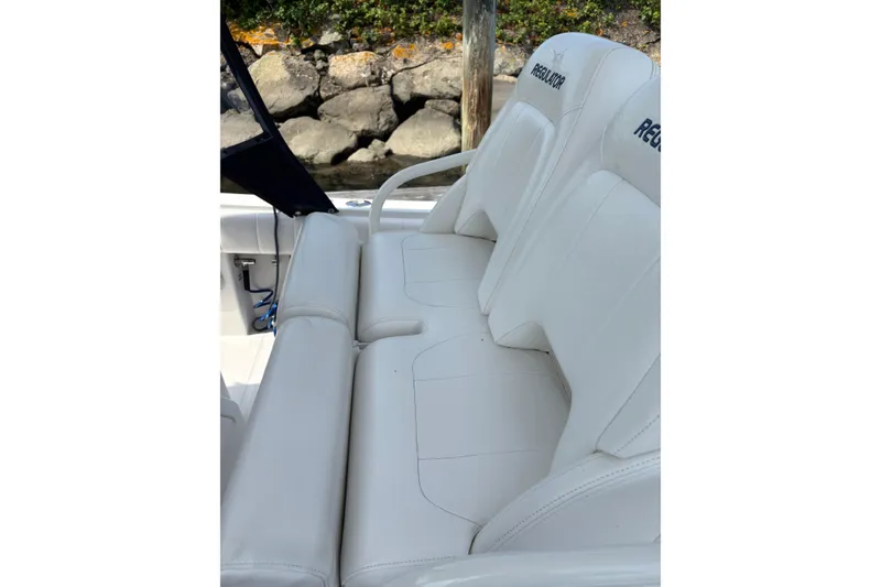 Slide: The Image of White leather seating on a 2015 Regulator 25 boat, near rocky shoreline. - 16