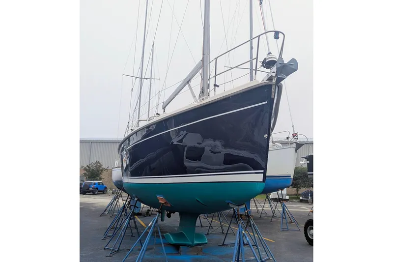 Slide: The Image of 2015 Hunter 37 sailboat on stands, blue hull, in a boatyard. - 62