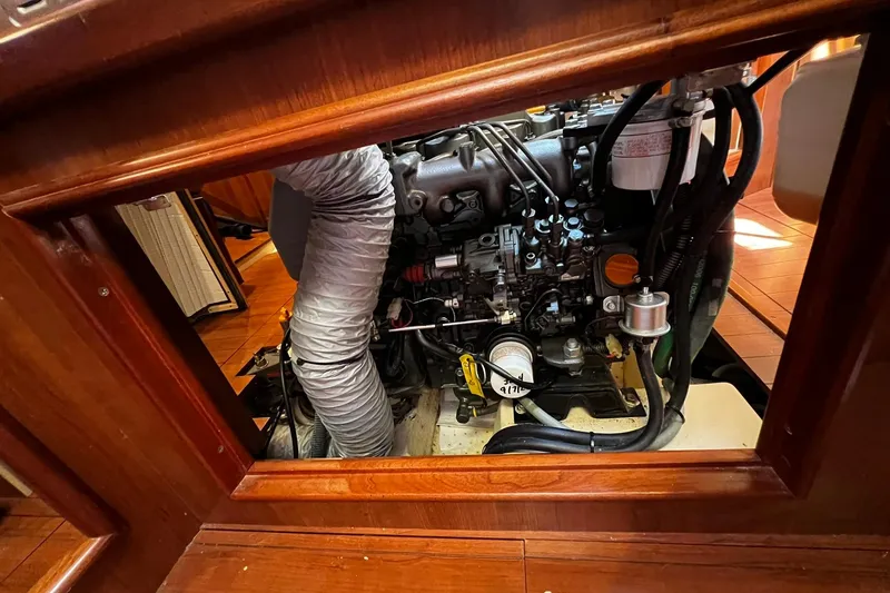 Slide: The Image of Engine compartment of a 2015 Hunter 37 sailboat, showcasing mechanical components and wooden interior. - 54