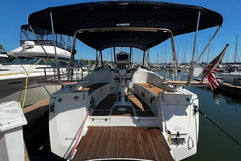 Slide: The Image of 2015 Hunter 37 sailboat docked at marina, featuring spacious cockpit and American flag. - 1