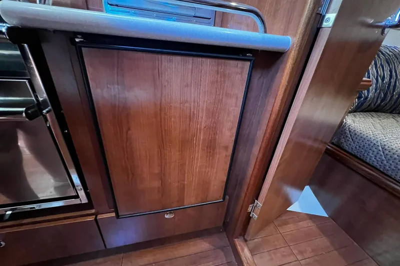 Slide: The Image of 2015 Hunter 37 yacht interior with wooden cabinetry and compact kitchen area. - 27