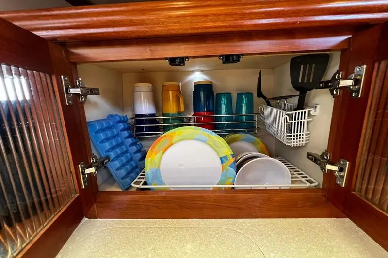 Slide: The Image of Cabinet with colorful plates, cups, and kitchen utensils in a 2015 Hunter 37 model. - 23