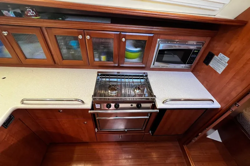 Slide: The Image of Modern galley kitchen in 2015 Hunter 37 yacht with stove, microwave, and wooden cabinetry. - 22