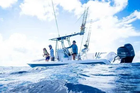 Slide: The Image of 2027 Contender 24 Sport boat with people fishing on open ocean under blue sky. - 2