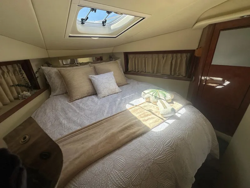 Slide: The Image of The 2006 Sea Ray 380 Sundancer cabin features a cozy bed with natural light from a skylight. - 12